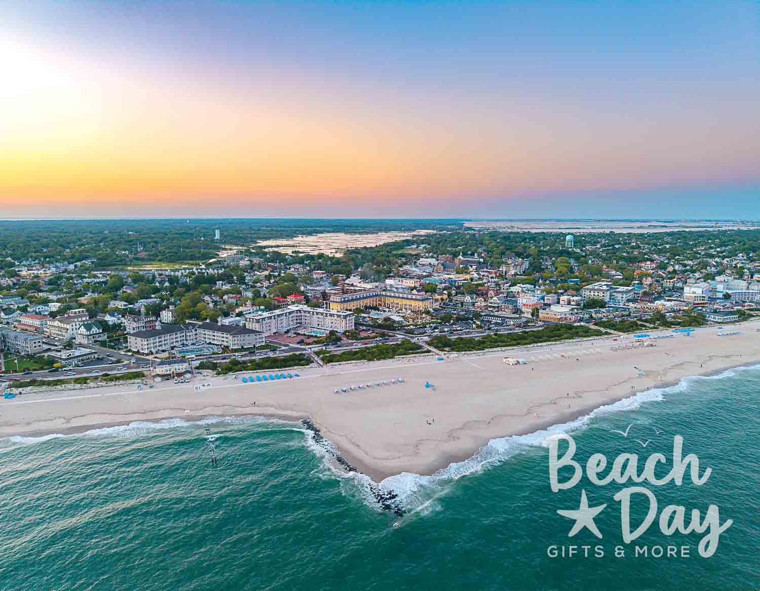 July: Aerial view of Cape May's beachfront, ocean waves, and seaside neighborhood